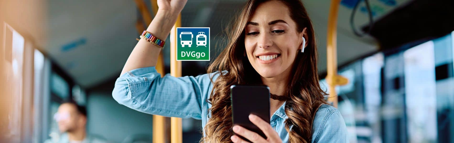 Frau steht mit Handy in der Hand im Bus