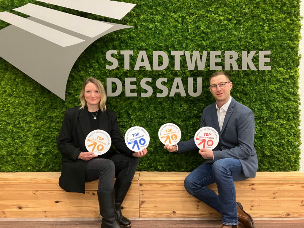 Top-Lokalversorger DVV-Mitarbeiter halten Siegel zum Top-Lokalversorger