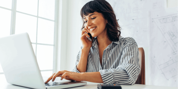 Frau arbeitet am Laptop und telefoniert