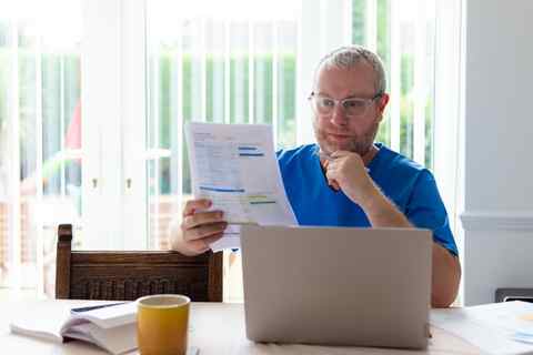 Arbeitsplatz mit Laptop und Dokumenten Mann arbeitet mit Laptop und Dokumenten an einem Tisch, helles Büro.