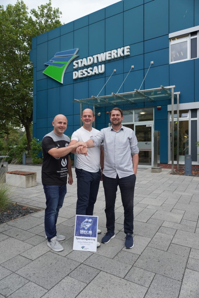 Dessau Stadtwerke Gebäude mit Menschen Drei Männer vor dem Stadtwerke Dessau Gebäude, lächelnd und handshake.